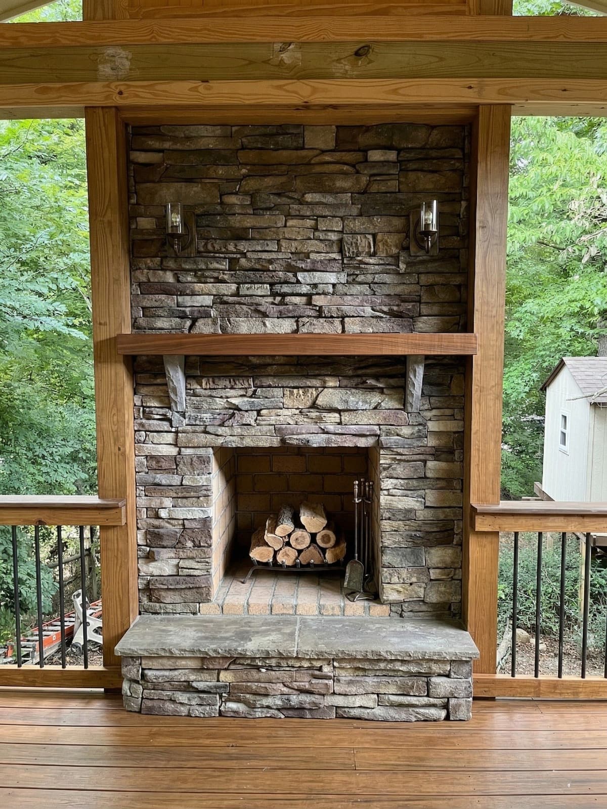 Outdoor stone fireplace with a raised hearth anchoring a paver patio