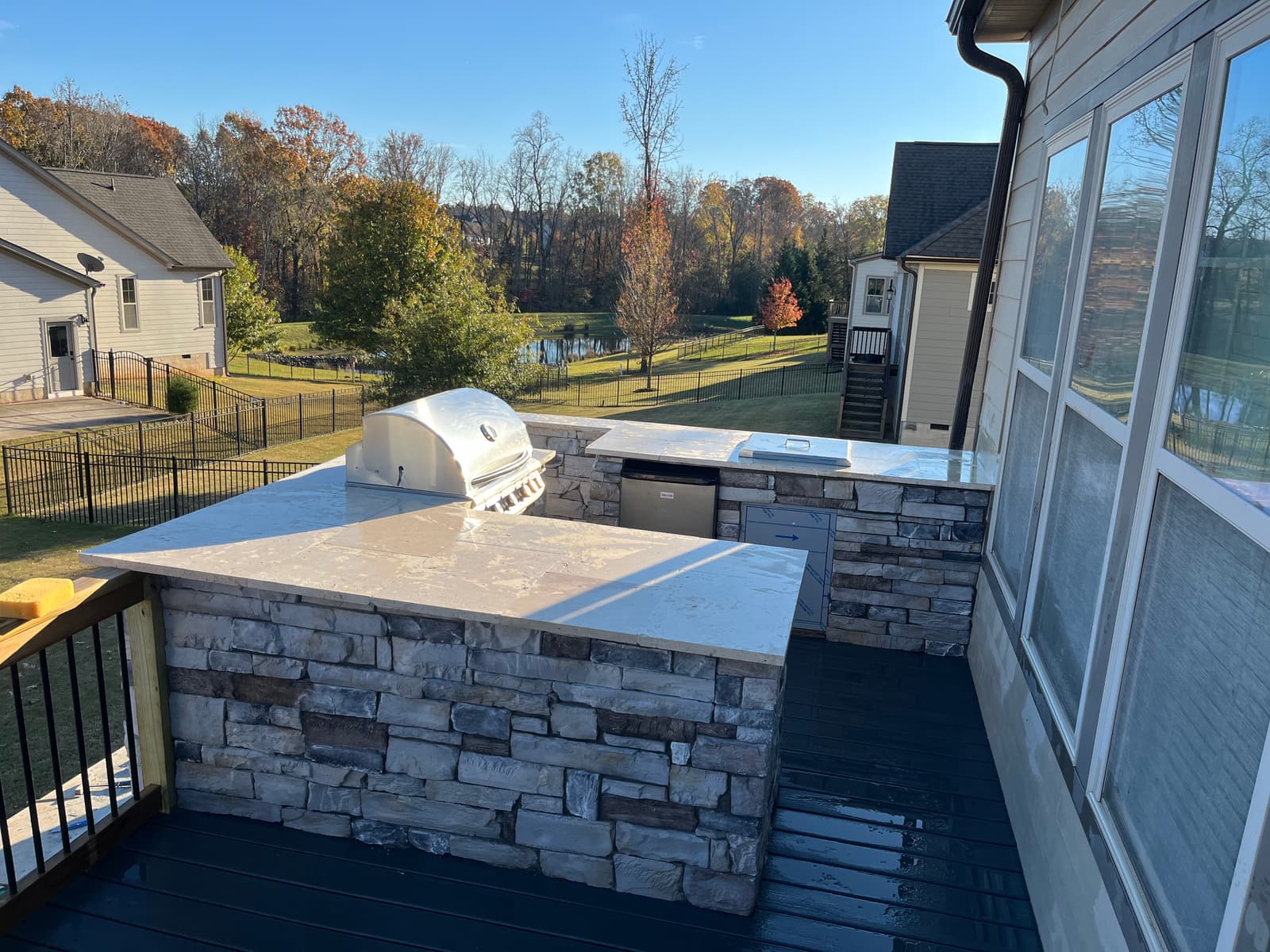 Full outdoor kitchen with a built-in grill, storage doors and a stone counter