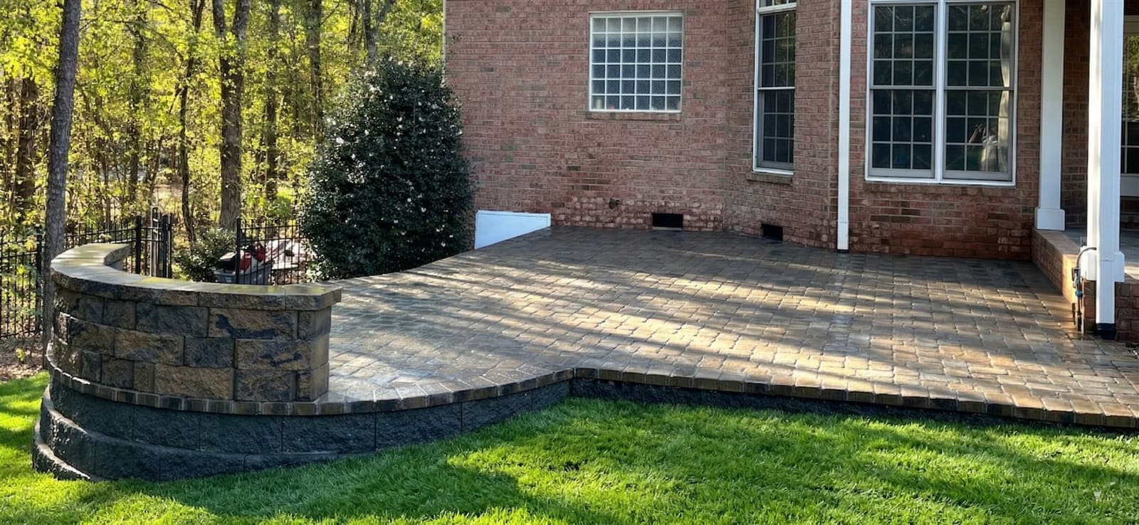 Paver patio with a stone border set into a Charlotte backyard on red clay subsoil